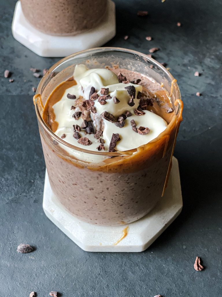 close up of a glass jar containing low glycemic high protein chocolate pudding textured No Oats with peanut butter, yogurt and cacao nibs on top