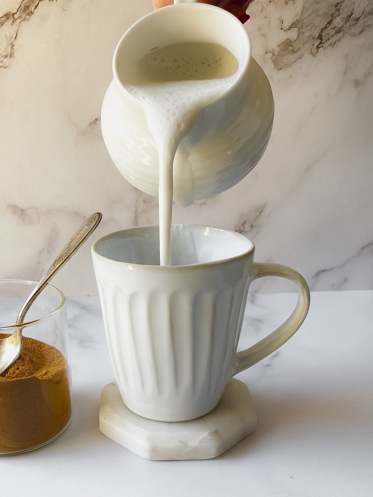 cashew milk pouring from a creamer into a mug