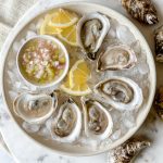 plate of 6 oysters on ice and a small dish of mignonette salsa