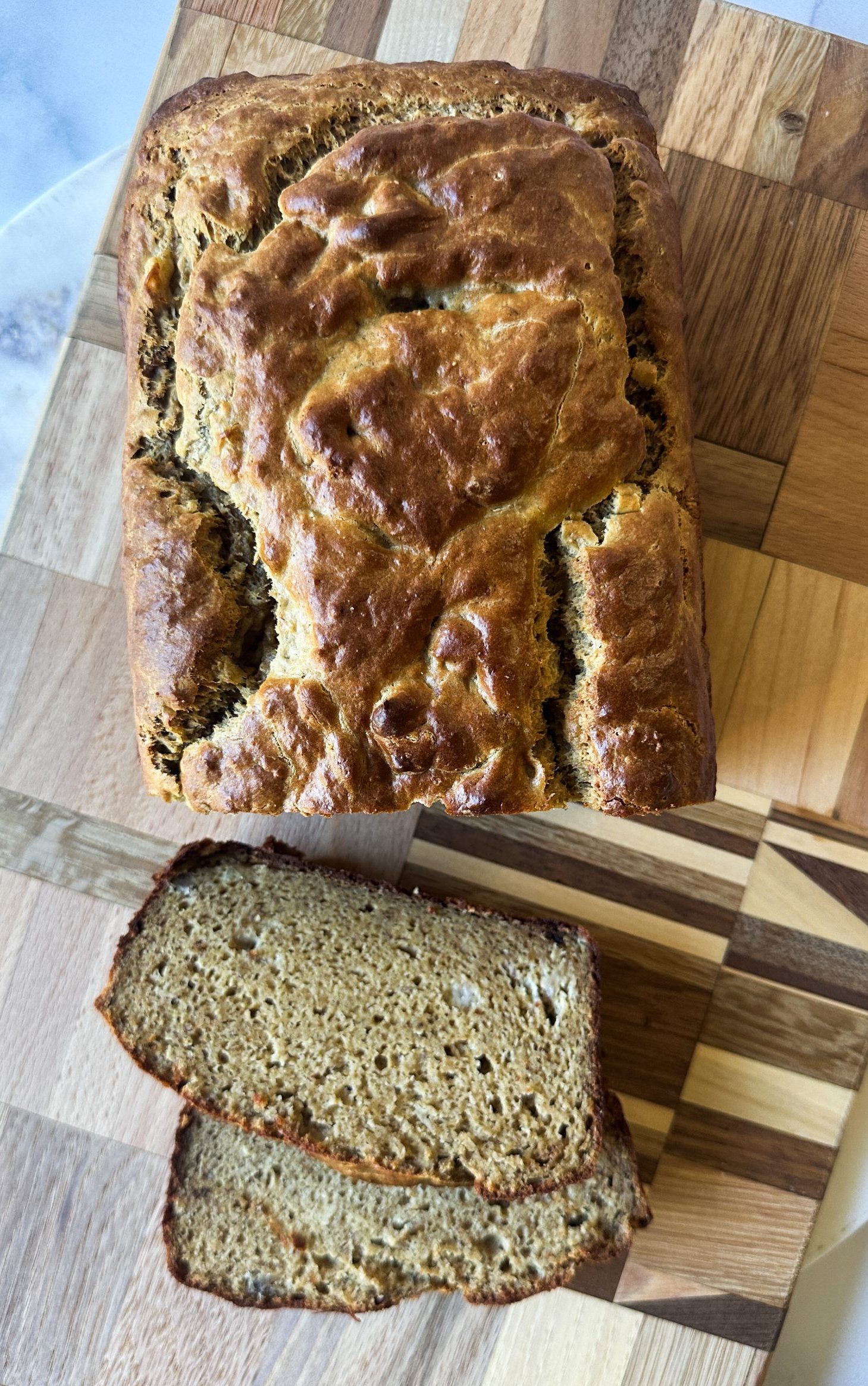 loaf of banana bread on a cutting board with 2 slices