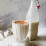 glass of eggnog with bottle of eggnog nearby
