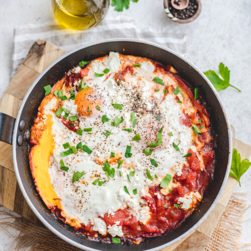 red shakshuka with feta and herbs in a skillet