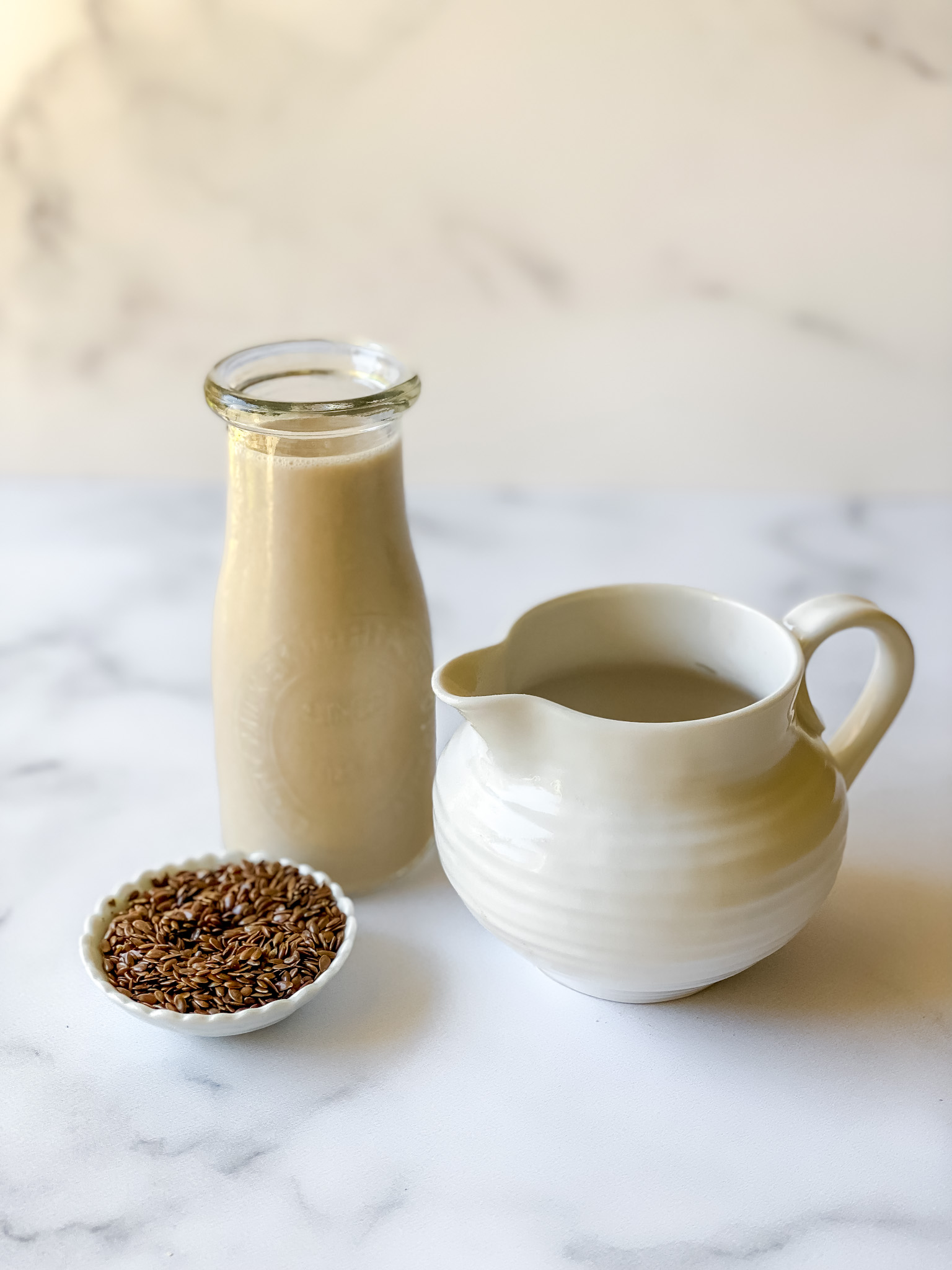 homemade flax milk in jug and creamer plus dish of flax seeds