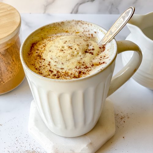 white mug of turmeric latte with cinnamon on top