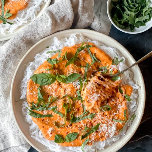 plate of konjac noodles topped with romesco sauce, cheese and basil