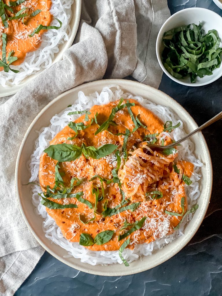 plate of konjac noodles topped with romesco sauce, cheese and basil
