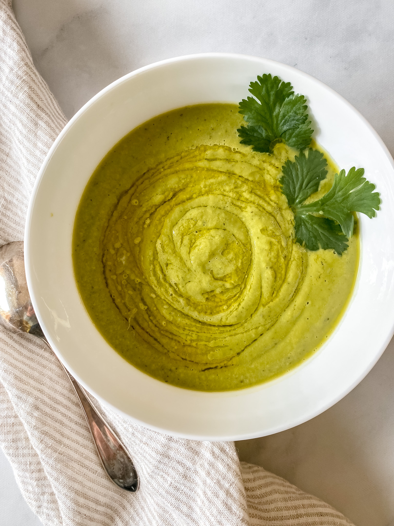 white bowl of vibrant green soup garnished with cilantro