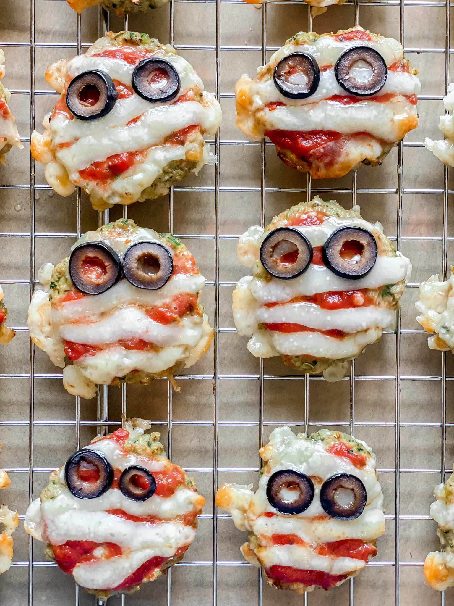 6 sausage patties with cheese strip and olives for eyes to make a "mummy"