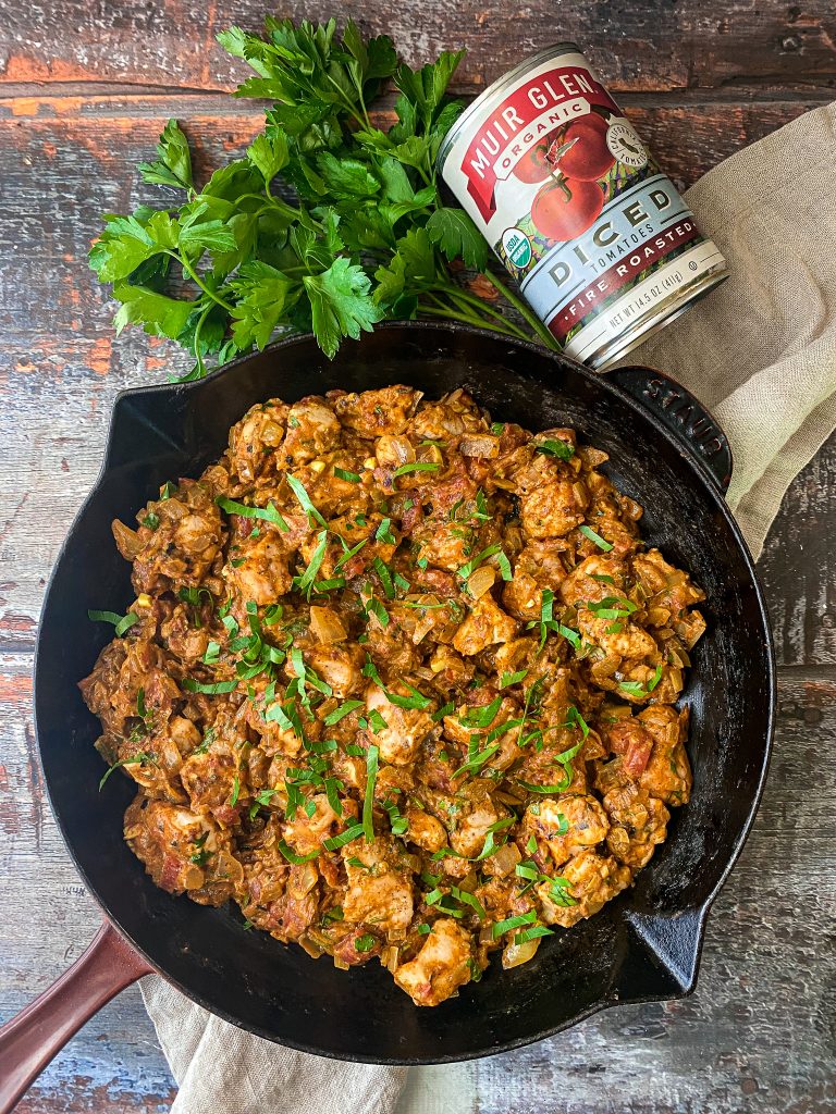 staub skillet with tomato chicken curry, garnished with cilantro