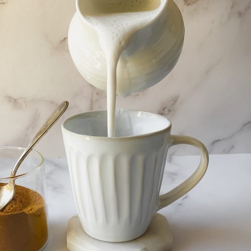 cashew milk pouring from a creamer into a mug