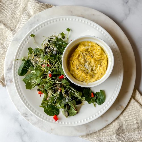 plate with green salad and ramekin of baked eggs