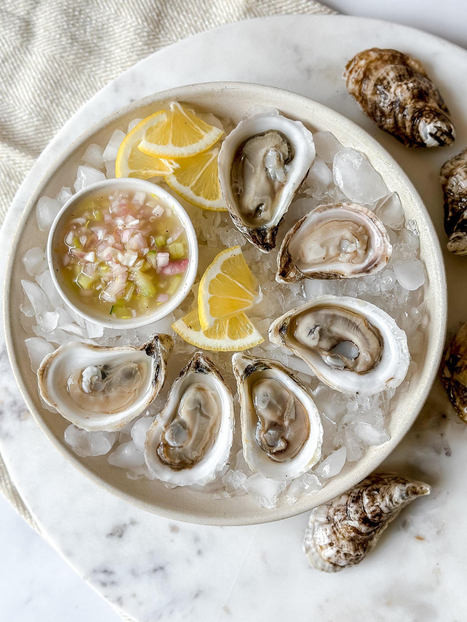 plate of 6 oysters on ice and a small dish of mignonette salsa