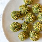 plate with vibrant green matcha protein balls rolled in crushed pistachios